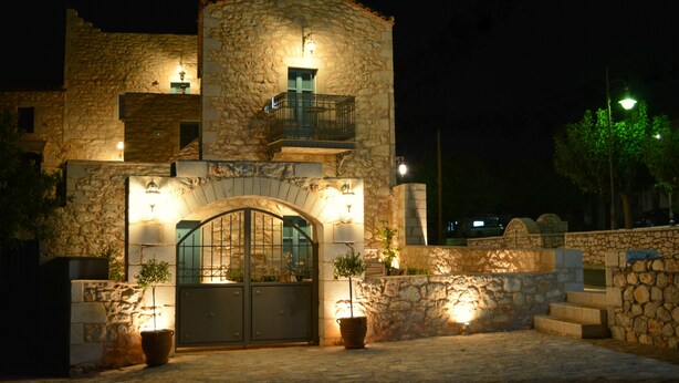 A stone building with a gated entrance, a balcony, and potted plants. - Olea (East Mani)