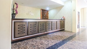 A reception desk with a patterned design, a potted plant, and a sign that reads "TIGUADORA". - OYO 1153 Tiga Dara Hotel & Resort Syariah (Pekanbaru)