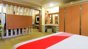 A hotel room with a bed, a desk, a wardrobe, and a mirror. - OYO 1153 Tiga Dara Hotel & Resort Syariah (Pekanbaru)