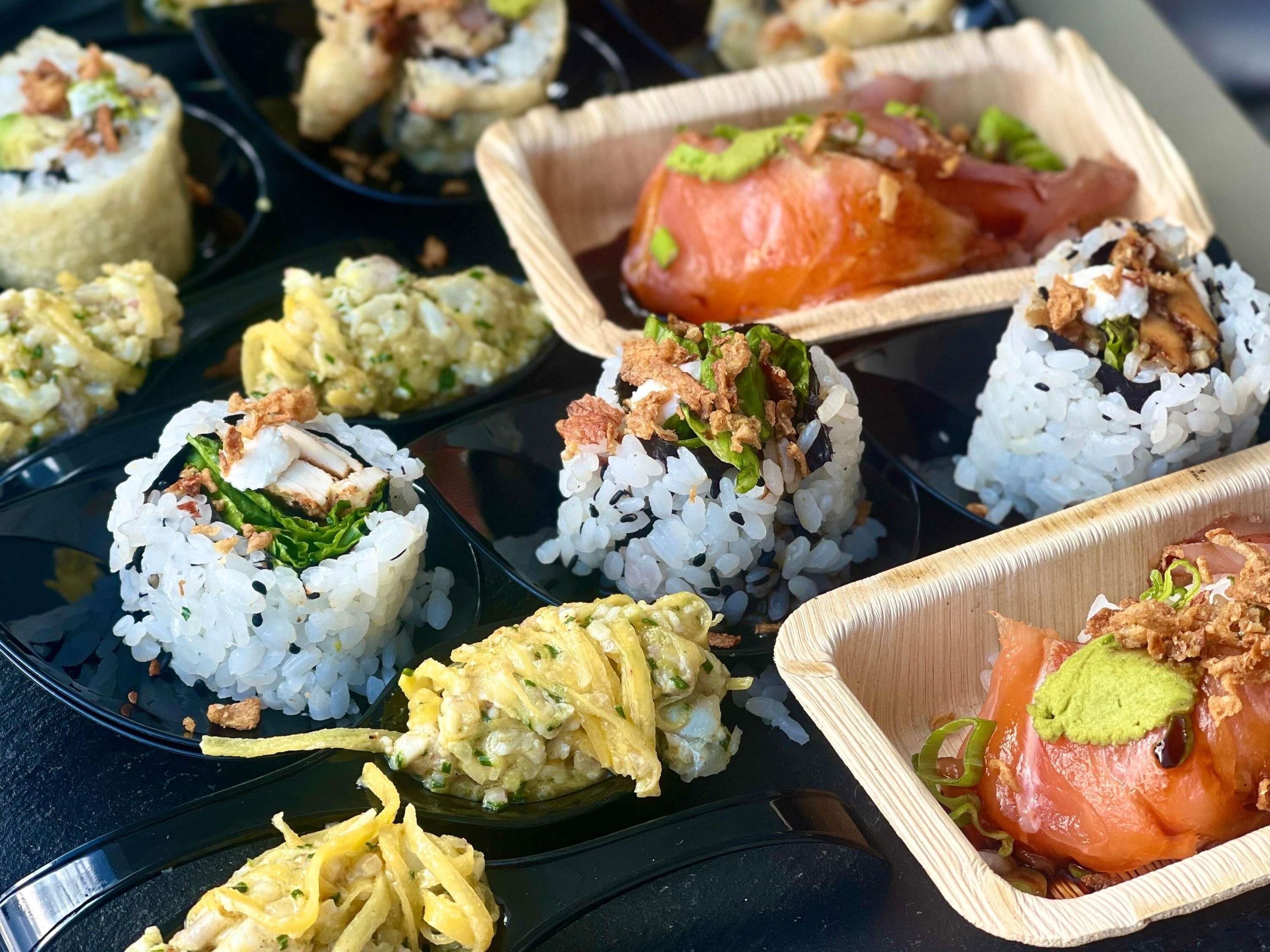 Un assortiment de sushis et de plats à base de riz, servis dans des contenants à usage unique.