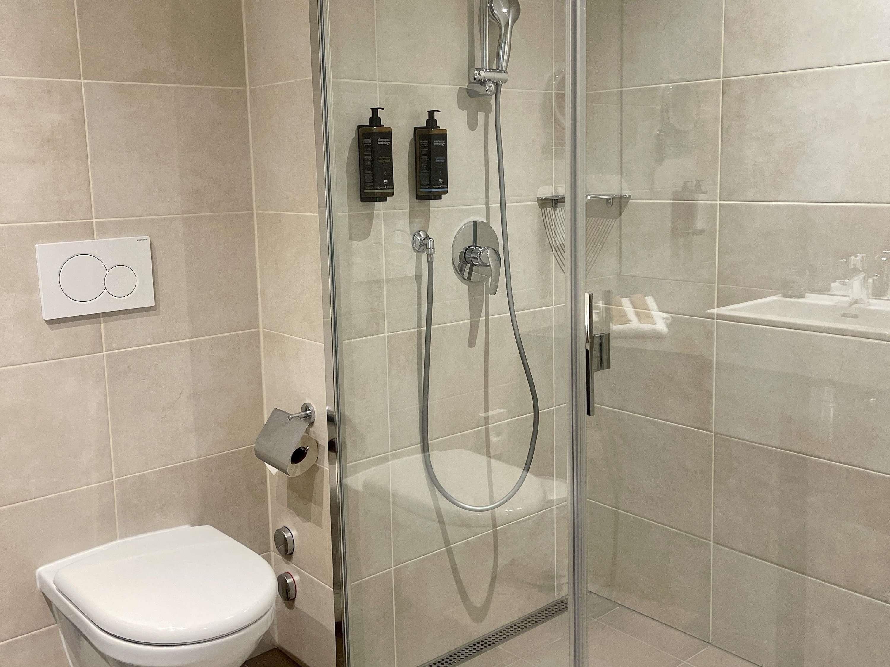 Un baño moderno con ducha de vidrio, inodoro y lavamanos.