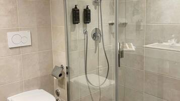 Un baño moderno con ducha de vidrio, inodoro y lavamanos.