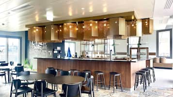 Een modern restaurant met een centrale bar, een zitgedeelte en vloertegels met een patroon.