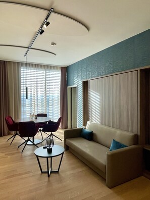 A modern living room with a round table, two armchairs, a sofa, and a large mirror. - Mercure Geneva Airport  (Meyrin)