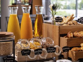 Un bufé de desayuno con alimentos identificados, incluyendo muesli, copos de maíz y chocolate.