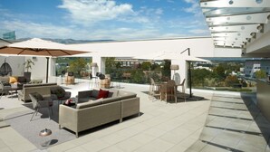 Terraço no telhado com mobiliário externo, guarda-sóis e vista para a paisagem ao redor.