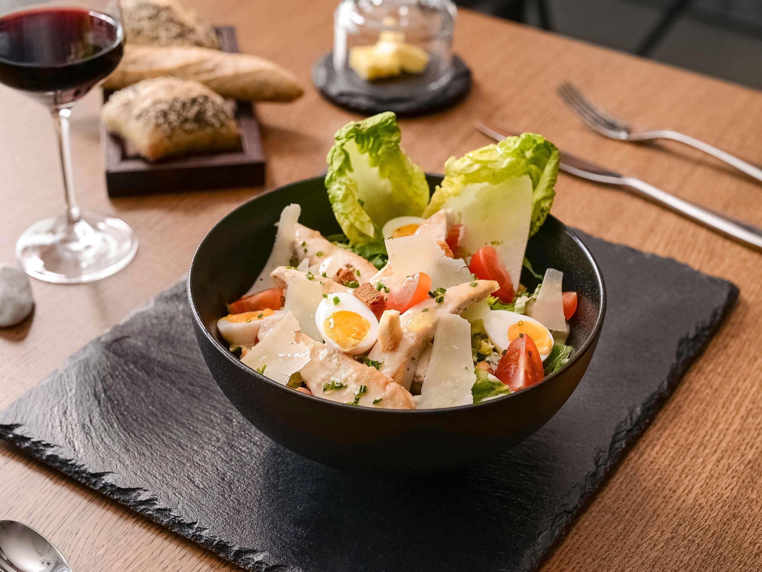 Een slakleisteen met een kom vol salade en verschillende ingrediënten.