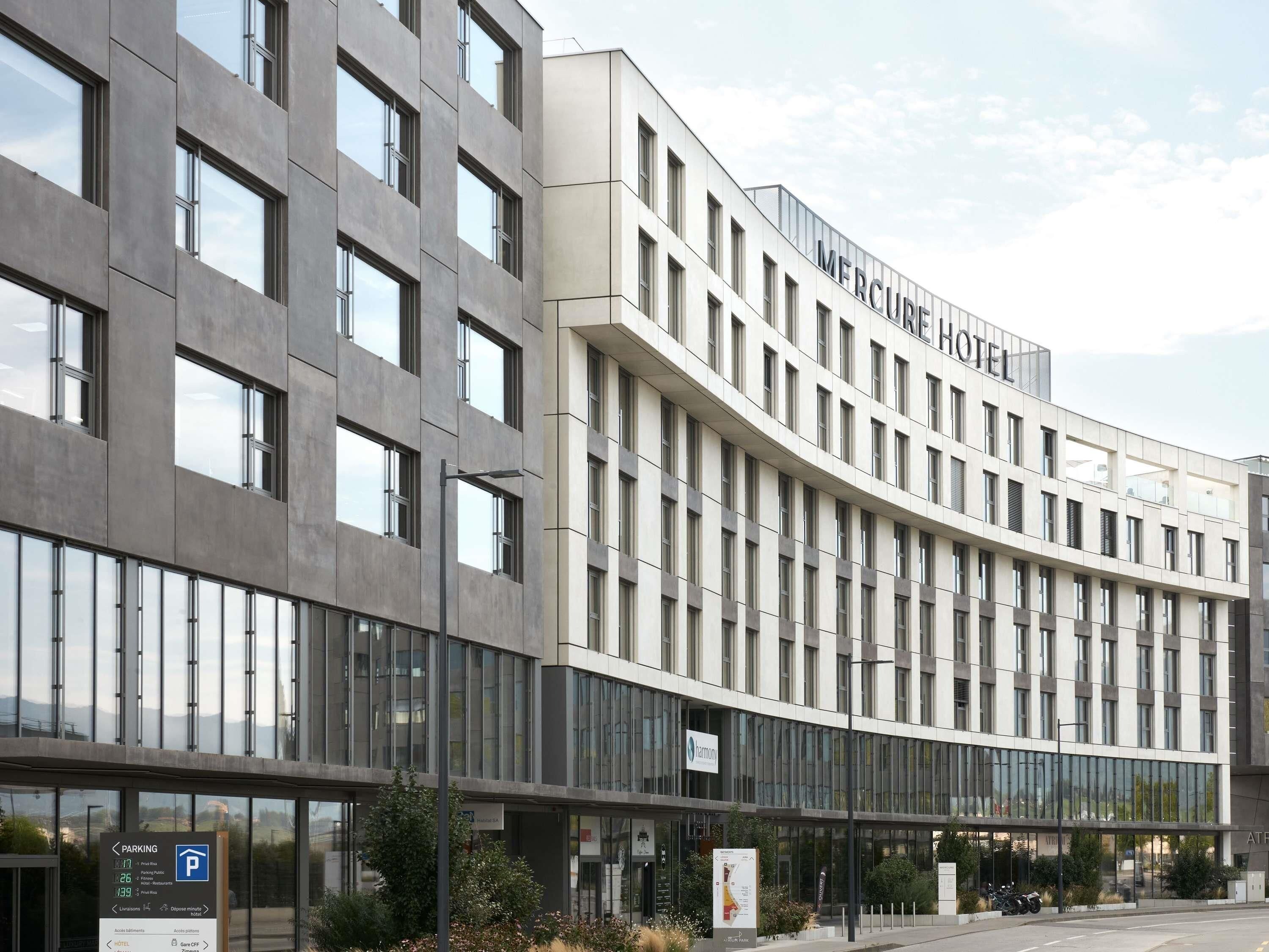 A modern hotel with a curved facade, large windows, and a prominent 'Mercure Hotel' sign.