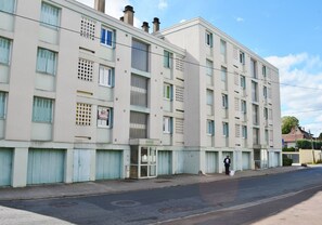 Un edificio de varios pisos con fachada plana, entrada a nivel de calle y una escalera visible que conduce a los pisos superiores.