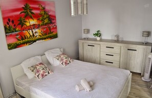 A bedroom with a bed, a nightstand, a cabinet, a painting, and a standing fan. - Apartment in Nevers for 6 to 8 people (Nevers)