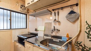 Una cocina compacta con un lavamanos de acero inoxidable, una ventana con persianas y un colgador para utensilios.