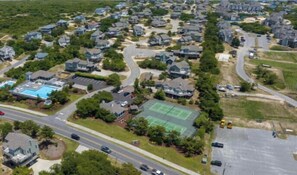 An aerial view of a residential area with houses, roads, and a tennis court.