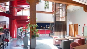 Un hall amplio con una escalera roja, zonas de estar y un mostrador de recepción.