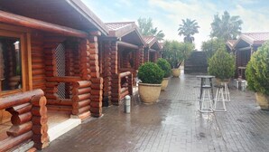 Un edificio de estilo cabaña de troncos con un patio de ladrillo, asientos exteriores y plantas en macetas.
