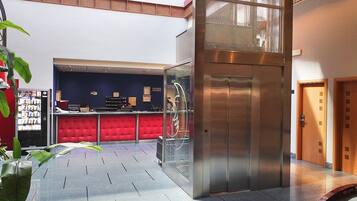 A lobby with a reception desk, red seating area, and an elevator.