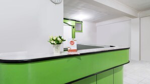 A reception area with a green counter, a clock, and a sign with a message. - OYO 1242 Penginapan Rb Syariah (Depok)