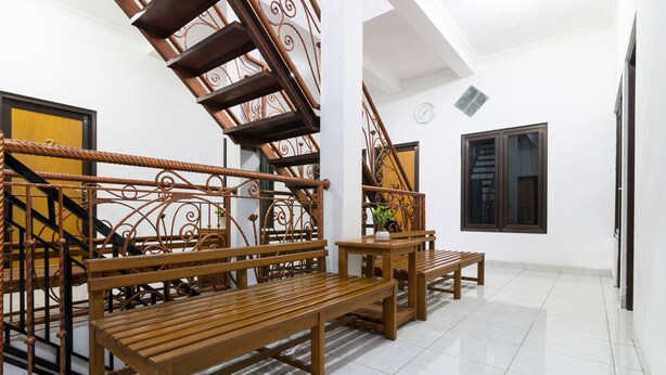 A staircase with ornate metal railings, wooden benches, and a clock on the wall. - OYO 1242 Penginapan Rb Syariah (Depok)