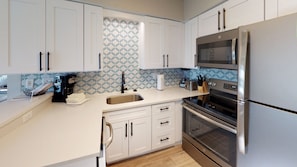Enjoy cooking in this well-equipped kitchen with sleek cabinetry, a spacious countertop, and appliances.