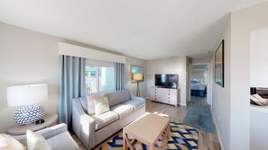 Relax in this inviting living space with a comfortable sofa, flat-screen TV, and floor lamp.