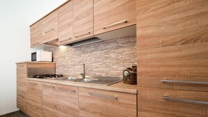 Eine moderne Küche mit Holzschränken, einer Edelstahl-Spüle und einer Mikrowelle.