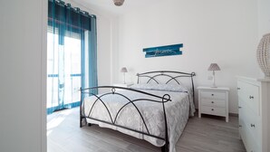 Ein Schlafzimmer mit einem Bett, Nachttischen, einer Kommode und einem Fenster mit Vorhängen.