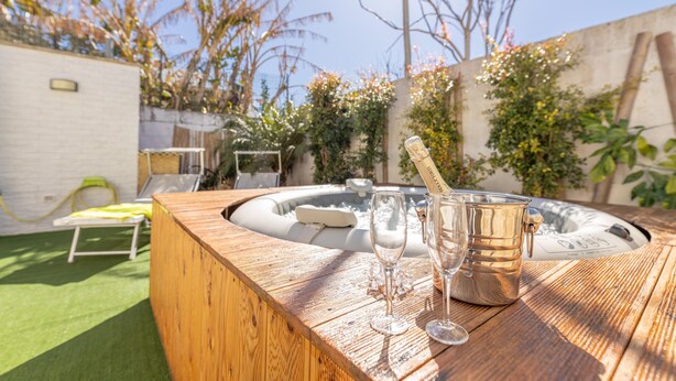 Ein Holztisch mit Whirlpool, zwei Gläsern und einer Champagnerflasche.