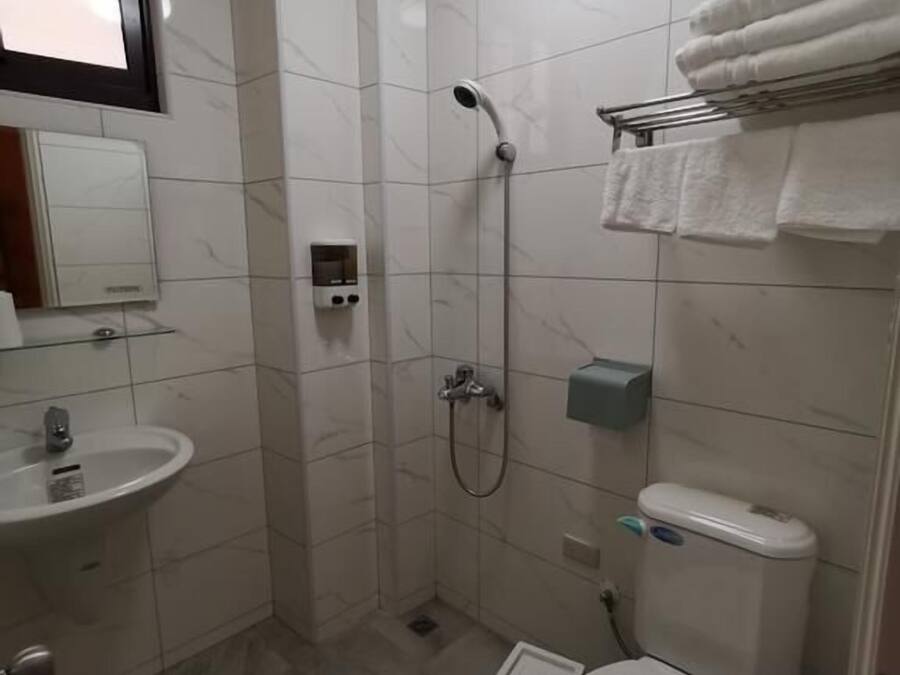 A small, modern bathroom with a shower, toilet, sink, and a mirror.