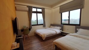 Habitación de hotel con dos camas, un escritorio, una silla y un televisor.