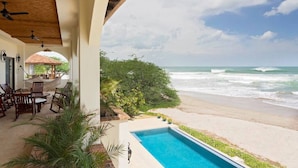 Ein Strandgrundstück mit Pool, Sitzgelegenheiten im Freien und Meerblick.