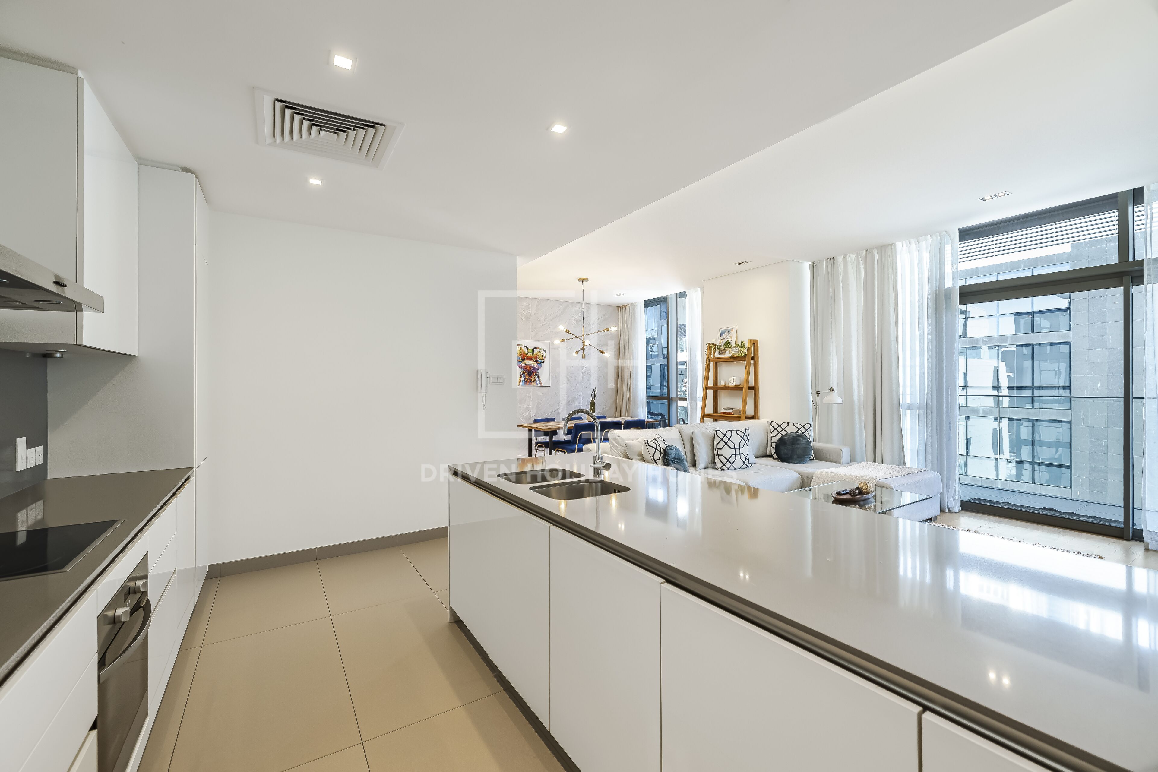 A modern kitchen with a large island, a dining area with a sofa and table, and a view of the city through large windows.