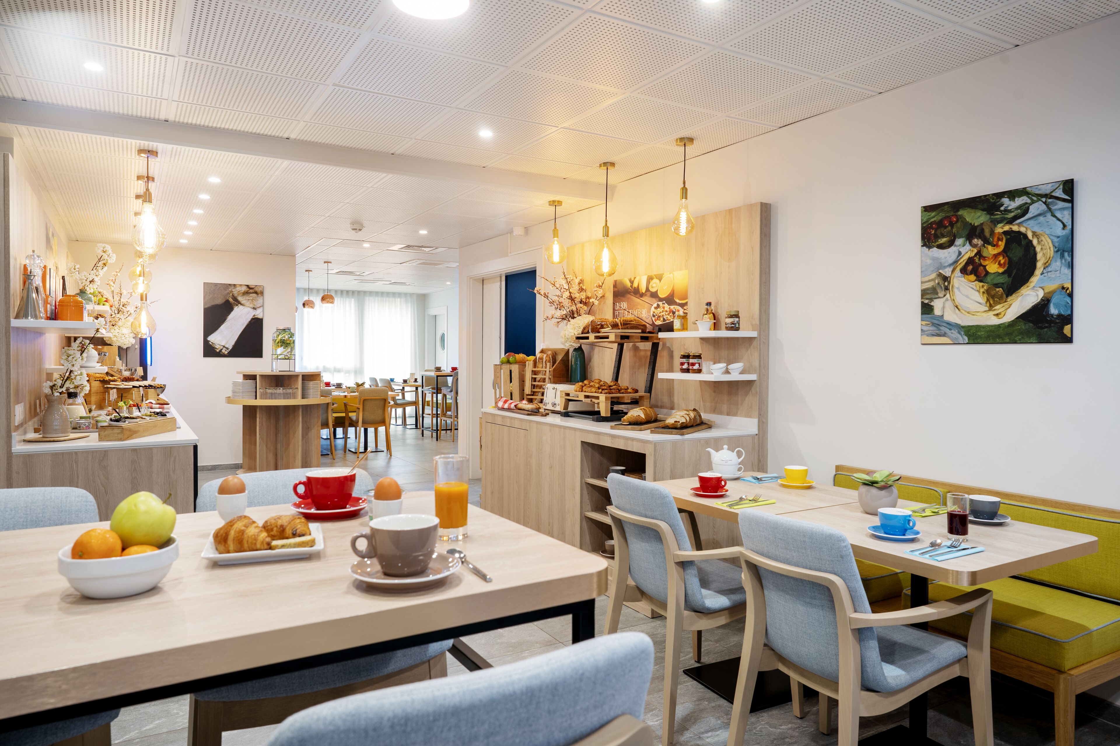 A modern dining area with a breakfast setup including fruits, pastries, and beverages.