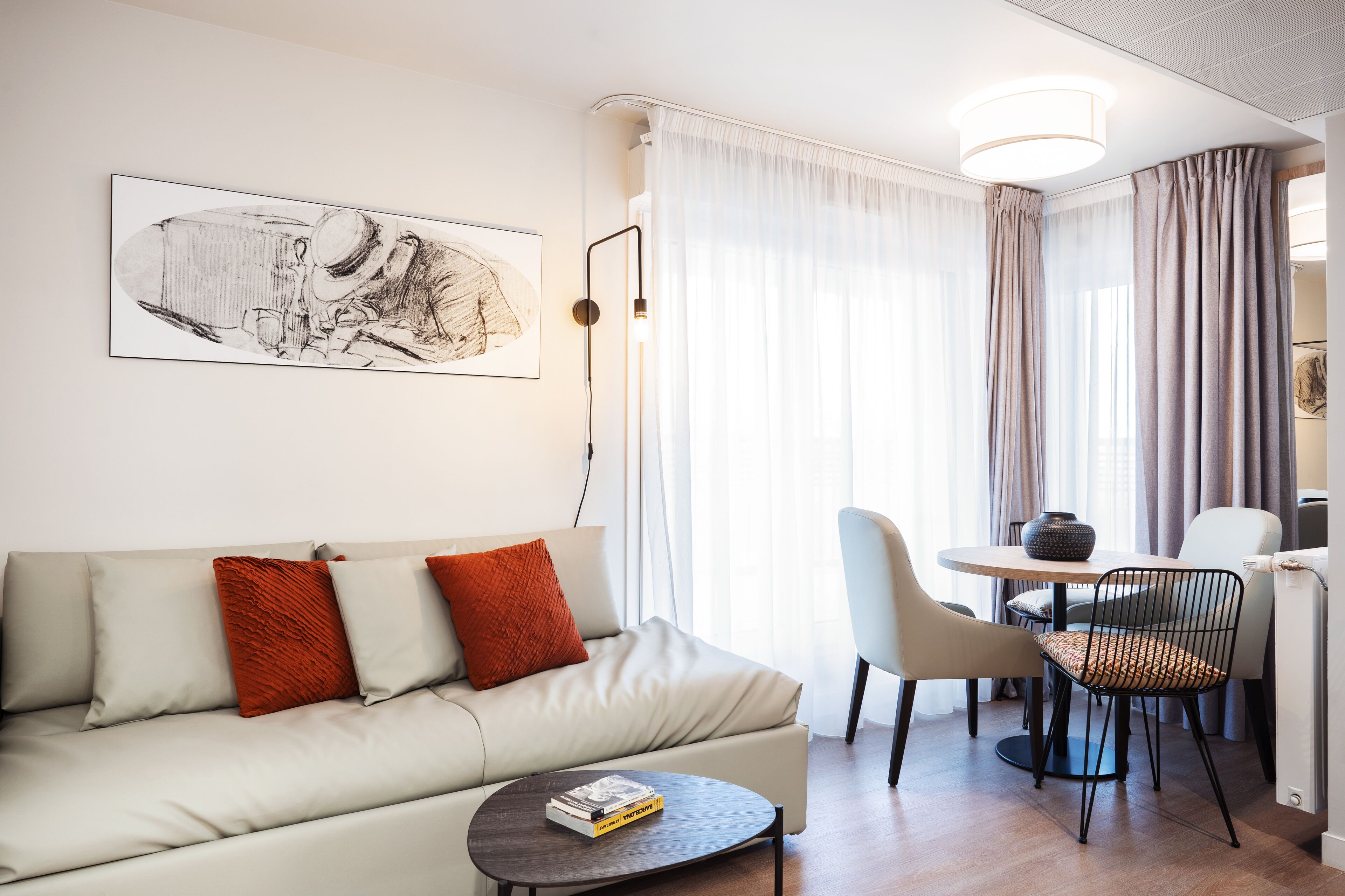 A modern living room with a sofa, a coffee table, and a dining area with chairs and a table.