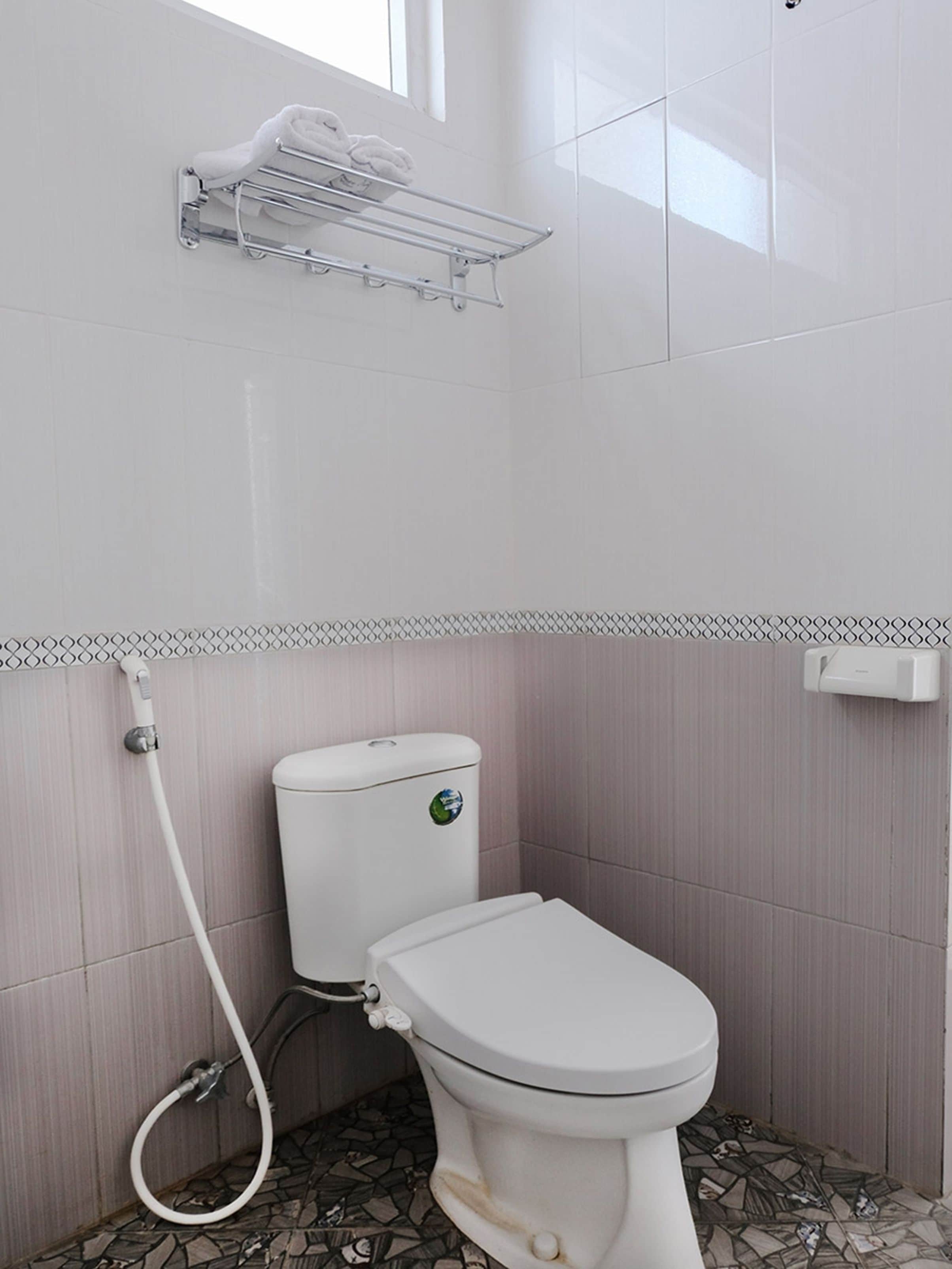 A bathroom with a toilet, a shower, and a towel rack.
