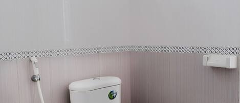 A bathroom with a toilet, a shower, and a towel rack.