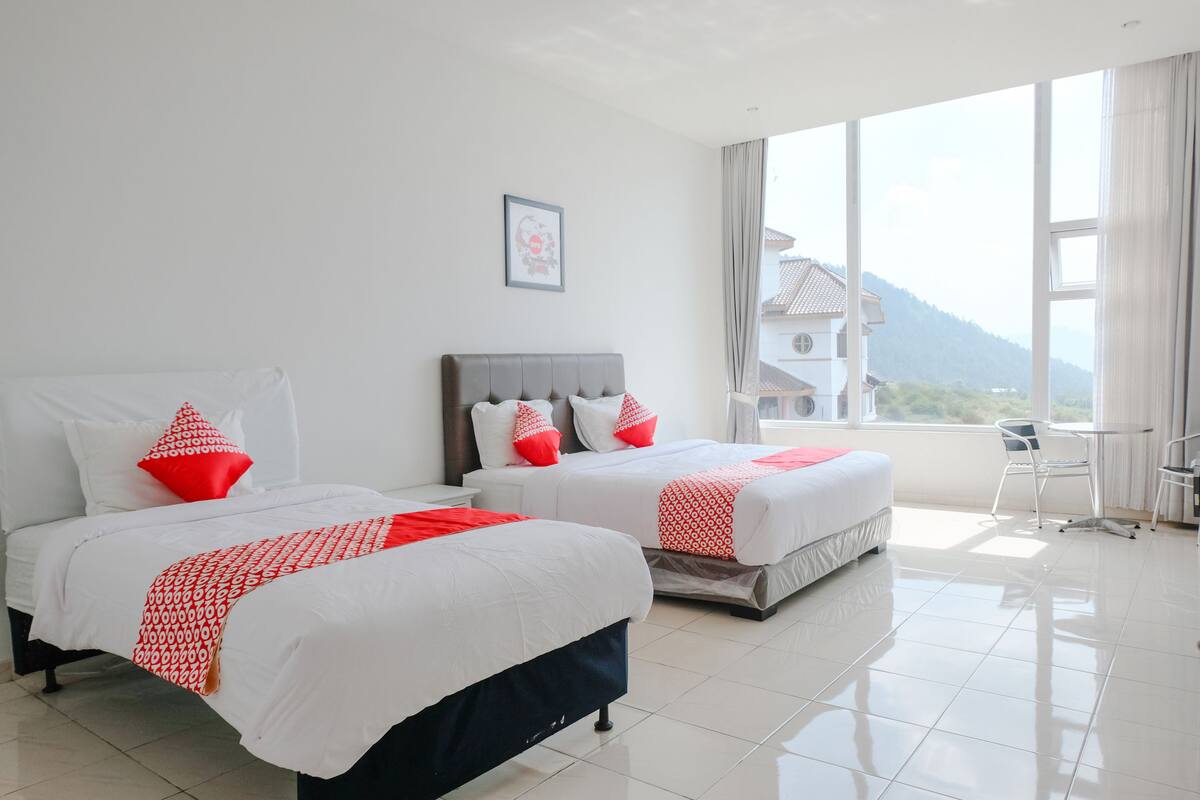 Une chambre d’hôtel avec deux lits, une petite table et une vue sur la montagne.