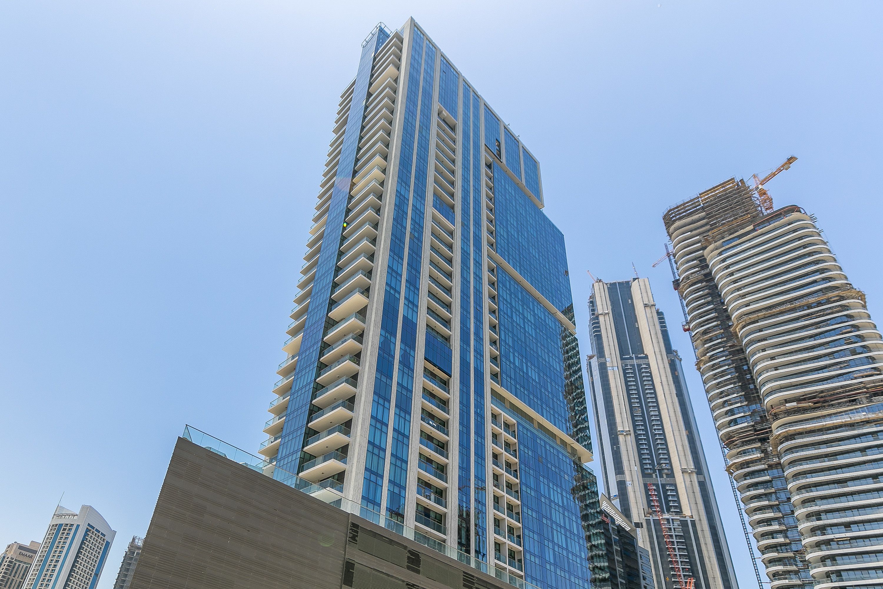A high-rise building with a modern design, featuring multiple balconies and a glass facade.