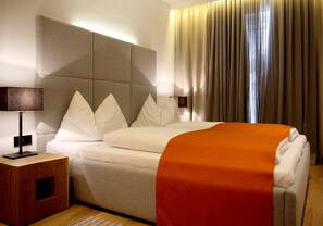 A hotel room with a bed, a nightstand, a lamp, and a window with curtains. - MountainVita (Untertauern)