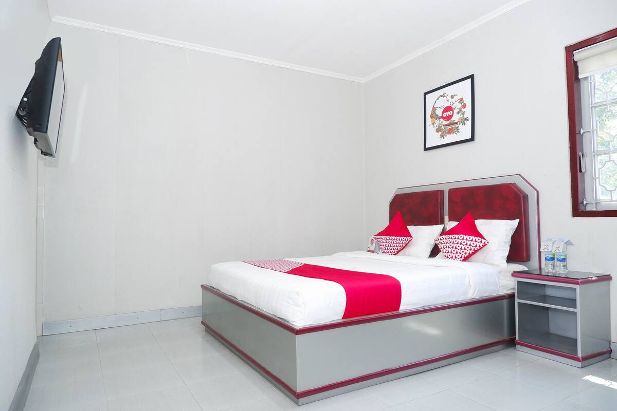 A neatly arranged bedroom with a bed, bedside tables, and a wall-mounted TV.