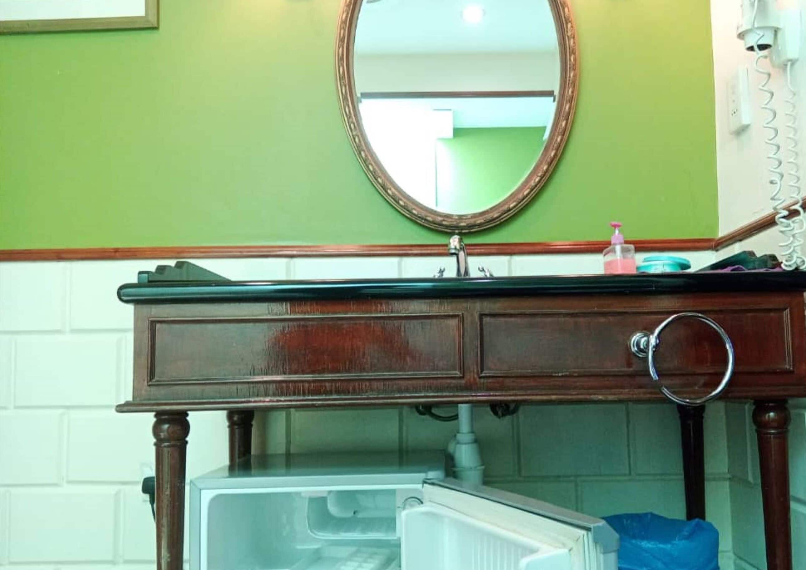 A bathroom with a wooden vanity, a mirror, and a white sink.