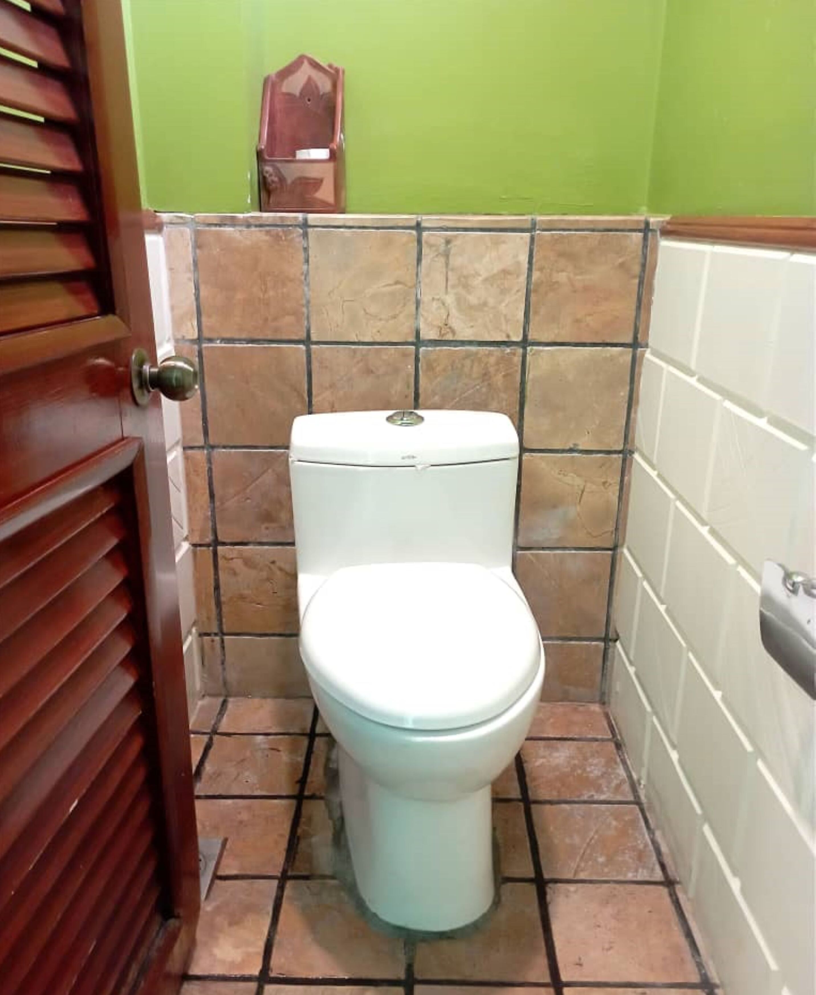 Eine Toilette in einem Badezimmer mit gefliestem Boden und Wänden.