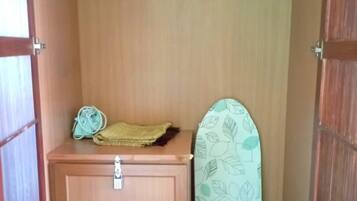 Un pequeño mueble de madera con cerradura, una toalla doblada y una tabla de planchar estampada.
