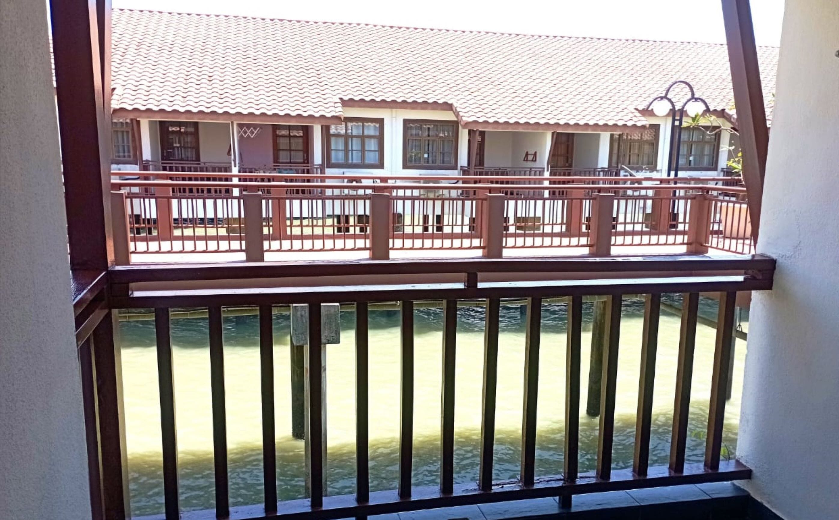 A balcony with a view of a building with a tiled roof and multiple windows.