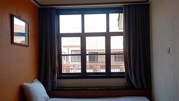 A hotel room with a large window, a bed, and a small table.
