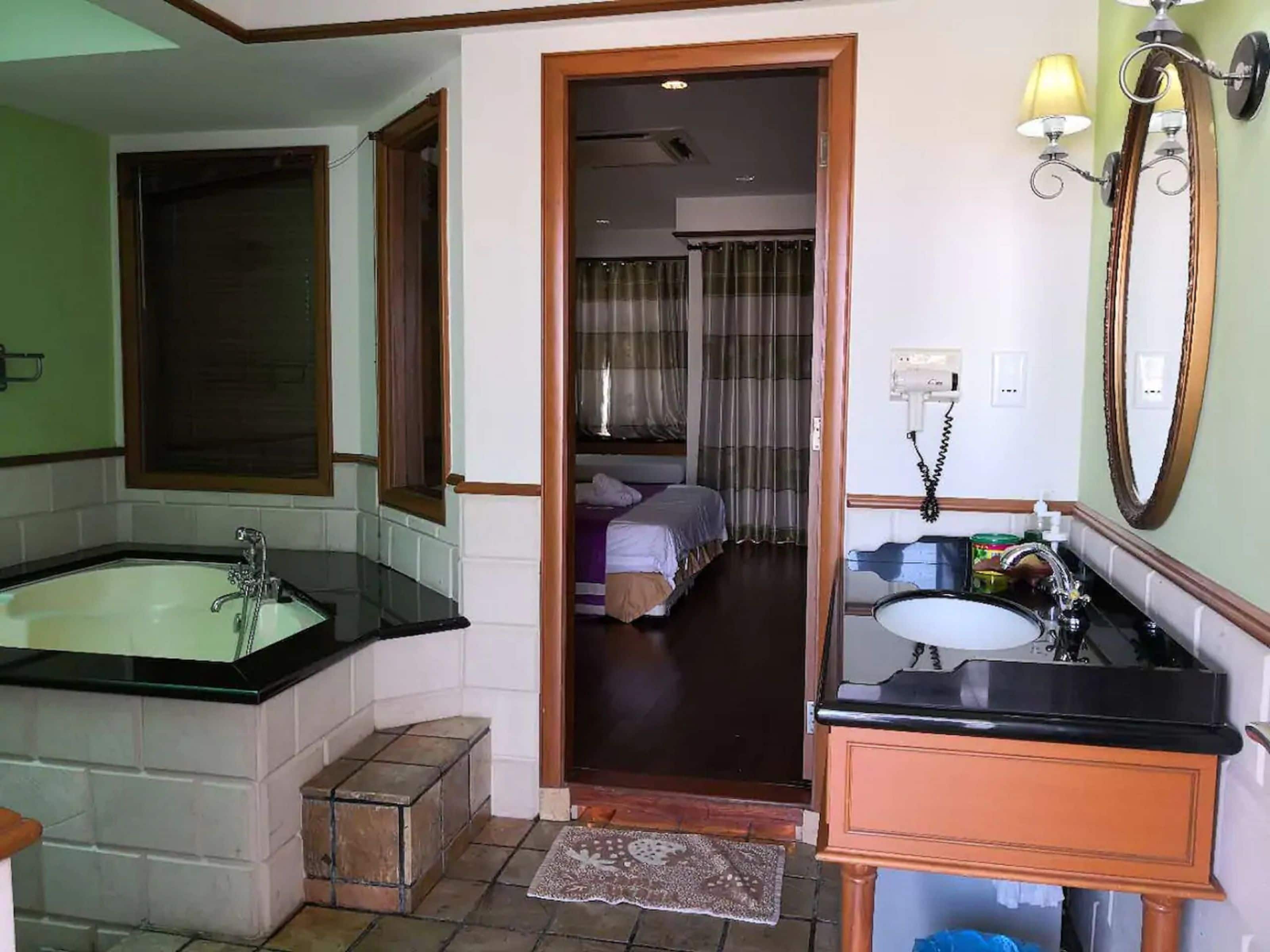 Un baño de hotel con una bañera grande, un lavamanos y un espejo.
