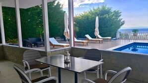 A covered outdoor area with a pool, lounge chairs, and a table with chairs. - Hotel Relax Dhermi (Himarë)