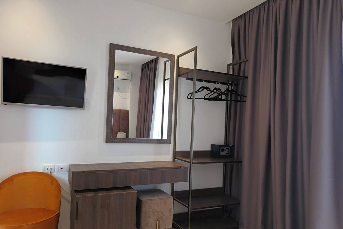 A modern bedroom with a bed, a TV, a wardrobe, and a desk.