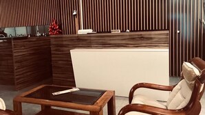 A reception area with a wooden reception desk, a waiting area with a wooden coffee table, and a reception sign. - Hotel Relax Dhermi (Himarë)