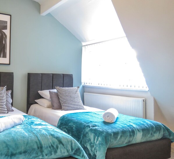 A bedroom with two beds, a skylight, and a radiator.