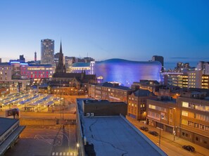A cityscape at dusk with illuminated buildings, including a distinctive dome-shaped structure with blue lighting.