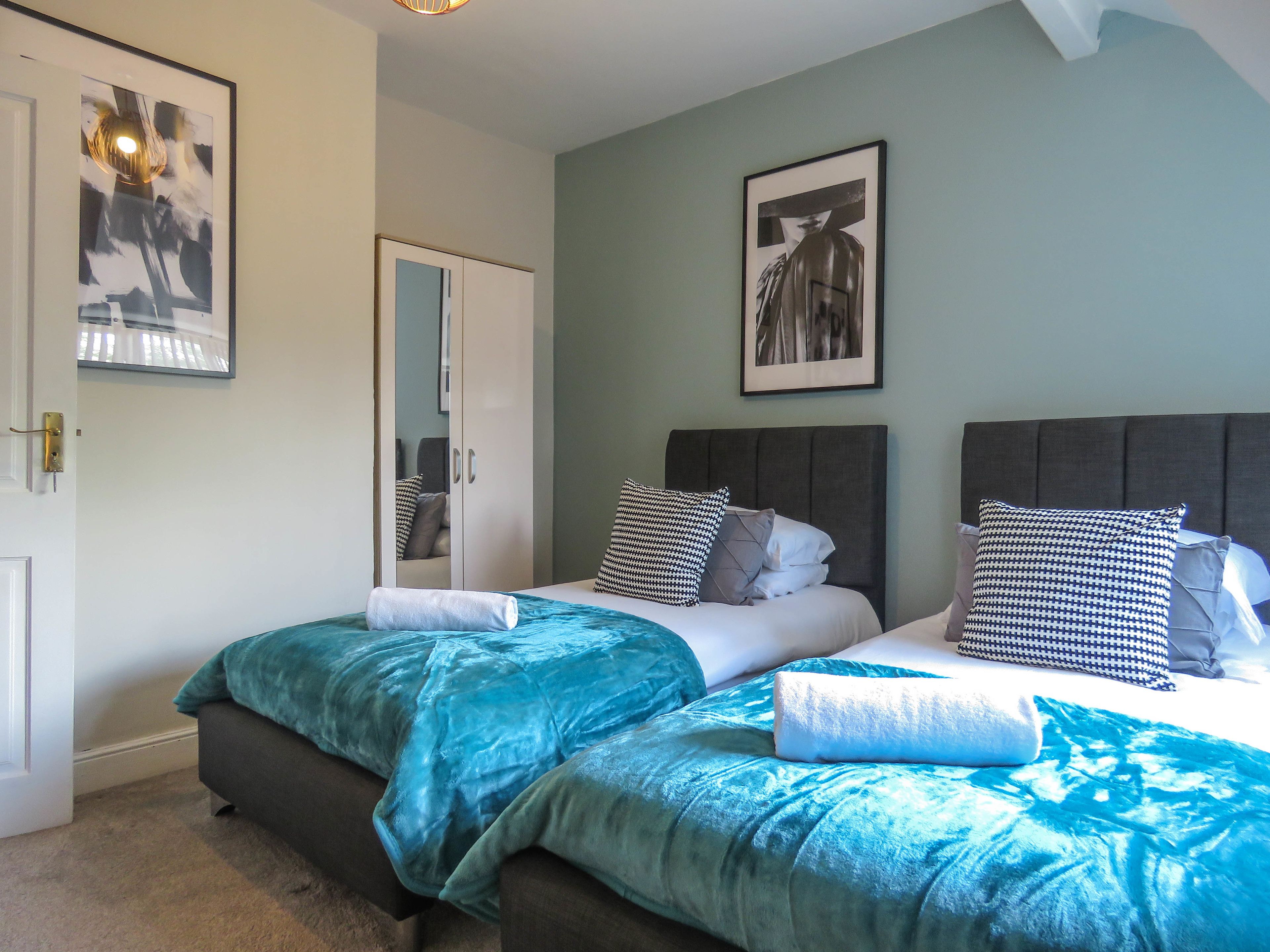 Een slaapkamer met twee bedden, een garderobe en een spiegel.